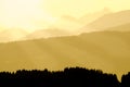 Spectacular view of mountain silhouettes. Yellow sunlight and sunbeams.