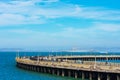 Spectacular view of weathered Municipal Pier opened for fishing and strolling. Background naval ship painted gray is passing in