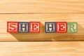 Spectacular wooden cubes with the word SHE HER on a wooden surface