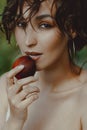 Spectacular young brunette eats peach in nature