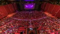 Spectators gather in the auditorium and watch the show in theatre timelapse. Large hall with red armchairs seats
