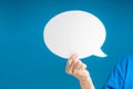Hand holding of a blank white speech bubble on a blue background Royalty Free Stock Photo