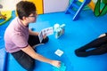 Speech therapist man treating a patient sitting on the floor.