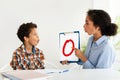 School boy learning letter O with tutor lady sitting indoor Royalty Free Stock Photo