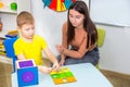 Speech Therapy. A young speech therapist is engaged in cubes with a boy. Learning the alphabet