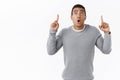 Speechless and curious, excited hispanic masculine guy, standing startled and astonished as pointing fingers up folding