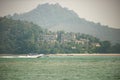 Speed Boat cruising the waters near a beach with apartments with traditional