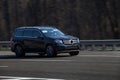 Mercedes black rides on the road. Against a background of blurred trees