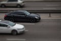 Mercedes black rides on the road. Against a background of blurred trees