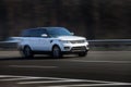 Range Rover white rides on the road. Against a background of blurred trees