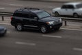 Toyota black rides on the road. Against a background of blurred trees