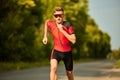 Speed and endurance. Motivated sportsman in sportswear running along the road, training outdoors