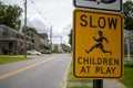 Urban outdoor yellow black street sign with a message of Slow children at play icon of running boy Royalty Free Stock Photo