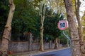 Speed limit sign. 50 kph or mph speed limit sign in the tree lined road. Royalty Free Stock Photo