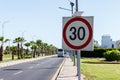 Speed limit sign with solar panel in the road with palm tree on a summer day. The speed limit is 30 km h on a gravel road