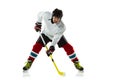 Young male hockey player with the stick on ice court and white background Royalty Free Stock Photo