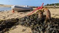 A speedboat beached on the sand moored to a rusty stake in the ground