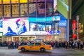 A Speeding Taxi in Times Square, New York City. Street and Stores with Bright Lights and Animated Screens Royalty Free Stock Photo