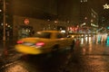 Speeding yellow taxi drives down rainy wet New York road at night with lights, New York Royalty Free Stock Photo