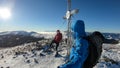 Speikkogel - A couple wearing snow shoes standing under a metal cross on top of Speikkogel in Austrian Alps. Fresh powder snow