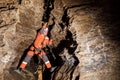 Speleologist descend by the rope in the deep vertical cave tunnel. Cave man hanging over abyss. View from the top og the tunnel. Royalty Free Stock Photo