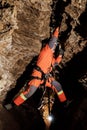 Speleologist descend by the rope in the deep vertical cave tunnel. Cave man hanging over abyss. View from the top og the tunnel. Royalty Free Stock Photo