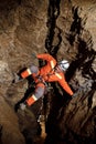 Speleologist descend by the rope in the deep vertical cave tunnel. Cave man hanging over abyss. Royalty Free Stock Photo