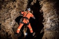 Speleologist descend by the rope in the deep vertical cave tunnel. Cave man hanging over abyss. Royalty Free Stock Photo