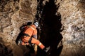 Speleologist descend by the rope in the deep vertical cave tunnel. Cave man hanging over abyss Royalty Free Stock Photo