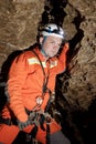 Speleologist descend by the rope in the deep vertical cave tunnel. Cave man hanging over abyss. View from the top og the tunnel. Royalty Free Stock Photo