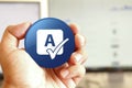 Spell check icon blue round button holding by hand infront of workspace background