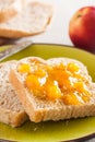 Spelt bread slices on a dish with peach marmalade close-up