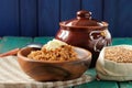 Spelt porridge buttered in wooden bowl and raw spelt in linen ba