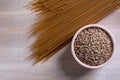 Spelt spaghetti and bowl with uncooked spelta grain on wooden table. Top view. Royalty Free Stock Photo
