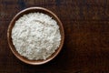 Spelt whole grain flour in dark wooden bowl isolated on dark bro