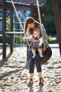 Spending a little time outdoors. Young mom on a park swing with a baby boy. Royalty Free Stock Photo