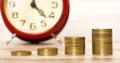 Spending money concept, coins with alarm clock in the background Royalty Free Stock Photo