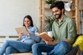 Spending nice time at home. Couple bonding to each other and smiling while reading book, tablet Royalty Free Stock Photo