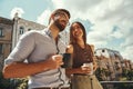 Spending nice time Two cheerful young colleagues holding cups and talking with smile while standing on the office Royalty Free Stock Photo