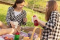 Spending time in the fresh air. Two young girls on a picnic eating, drinking lemonade, having fun, laughing, talking Royalty Free Stock Photo