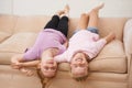 Spending time with a friend. Two young girls lying upside down on a couch. Royalty Free Stock Photo