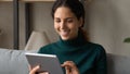 Excited millennial latina female using modern electronic tablet at home Royalty Free Stock Photo