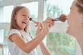 Spending time together. Happy delighted mother and her little adorable daughter are standing and holding brushes while doing make-