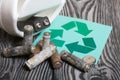 Spent finger-type batteries coated with corrosion. Waste recycling sign. Near the recycling bin. They lie on brushed pine boards Royalty Free Stock Photo