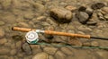 Spey fly rod and reel resting on wet rocks beside a river Royalty Free Stock Photo