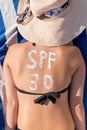 Spf 30 word is drawn with sunblock on woman`s back lying on the sunbed at the beach. Sun protection factor concept Royalty Free Stock Photo