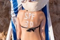 Spf 30 word is drawn with sunblock on woman`s back lying on the sunbed at the beach. Sun protection factor concept Royalty Free Stock Photo