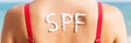 SPF word made of sunblock at woman`s back at the beach. Sun protection factor concept