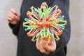 Sphere hoberman, a folding ball of rainbow color in the girls hand