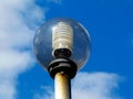 Sphere shaped street lamp lens under blue sky with white clouds Royalty Free Stock Photo